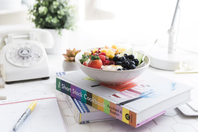 Bowl of fruit on top of cookbook