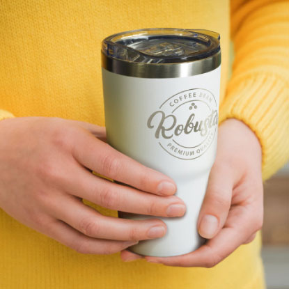 Woman in yellow jumper holding promotional travel mug