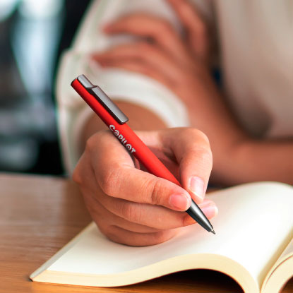 Person using a promotional pen to write in a notebook