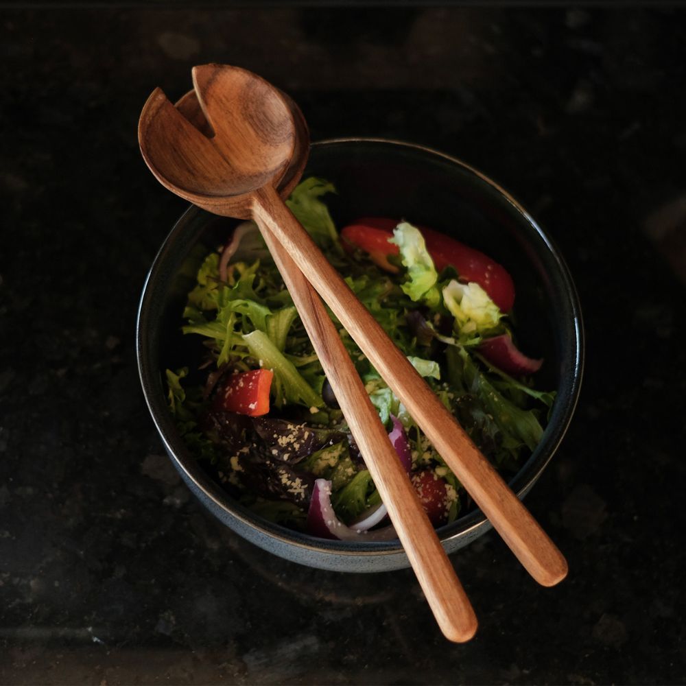 Wooden Salad Servers for Sustainable Promotional Gifting Wooden salad servers resting on a bowl of fresh salad, showing practical sustainable promotional merchandise suited to customer gifting and referral campaigns.