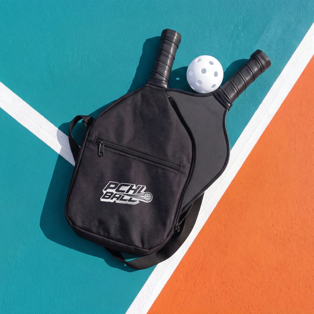 Custom Branded Pickleball Paddle Bag & Promotional Sports Accessories Black custom branded pickleball paddle bag with two paddles and a white pickleball on a colourful outdoor court, showcasing promotional sports merchandise.